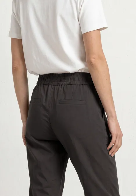 Rückenansicht einer Person in weißem T-Shirt und schwarzer Hose mit elastischem Bund und Gesäßtasche.