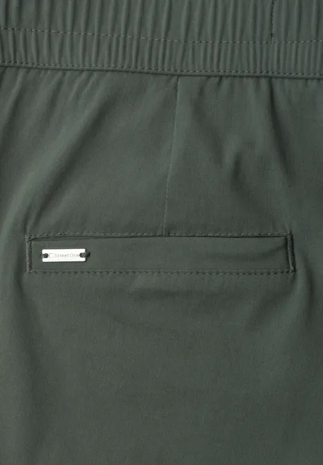Donkergroene stoffen broek met elastische taille en een achterzak met metalen plaatje.