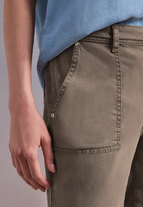 Nahaufnahme einer Hand an der Tasche khakifarbener Hose und einem hellblauen Oberteil