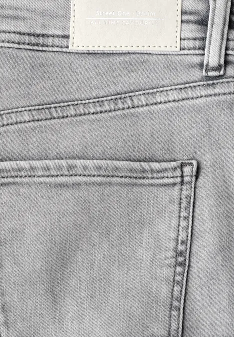 Detailaufnahme einer hellen Jeanshose mit Gesäßtasche, Gürtelschlaufe und unbeschriftetem Lederpatch am Bund.