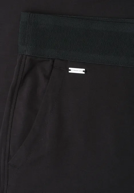 Zwarte broek met elastische taille, zijzak en klein metalen logo.