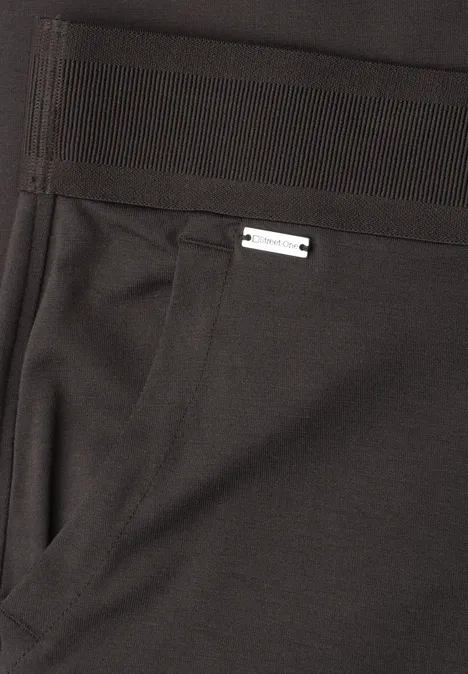 Zwarte broek met zijzak en een klein zilverkleurig label boven de zak.