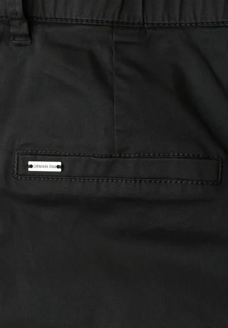 Nahaufnahme einer schwarzen Hose mit Gesäßtasche und kleinem Metall-Badge.