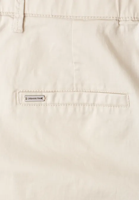 Nahaufnahme einer beigen Hose mit aufgesetzter Rücktasche und kleinem Markenetikett.