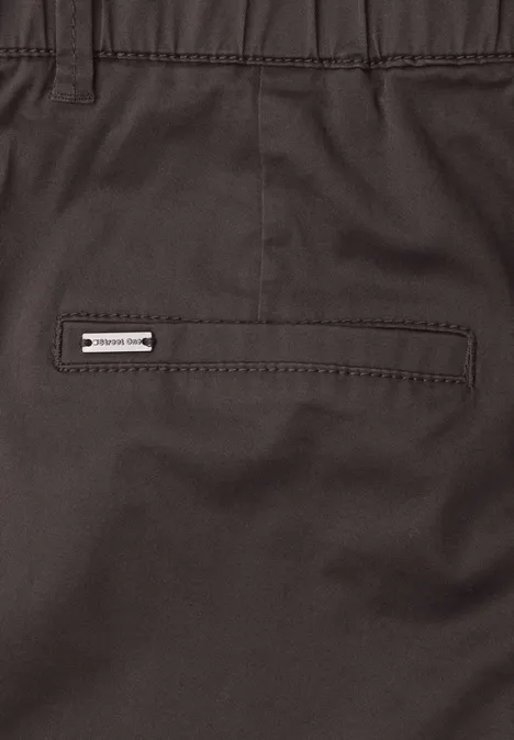 Close-up van een donkere broek met achterzak en klein merklabel.