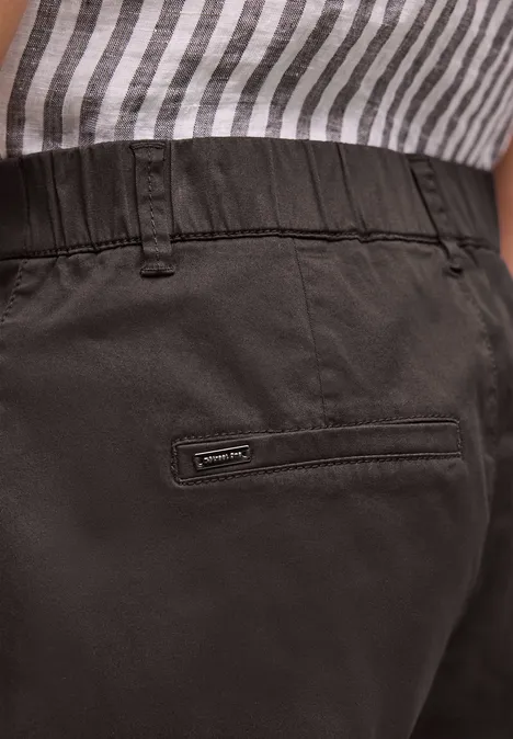 Close-up van een persoon in gestreept shirt en zwarte broek met achterzak