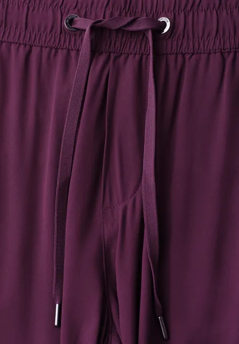 Blick auf die Taille eines bordeauxroten Hosenbeins mit elastischem Bund und Kordelzug.