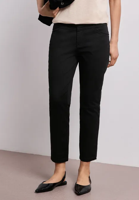 Zwarte, rechte damesbroek gecombineerd met puntige ballerina's en een licht topje.