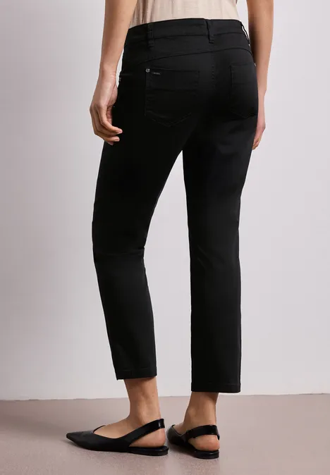 Zwarte, enkelhoge, slanke broek met achterzakken, gecombineerd met zwarte slingback-ballerina's.