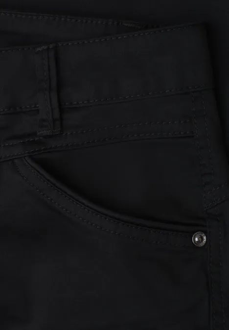 Zwarte spijkerbroekzak met zichtbare stiksels en metalen klinknagel.