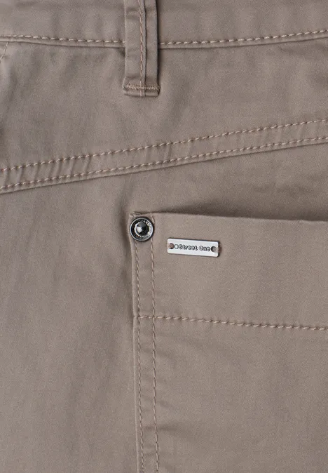 Vue rapprochée d’un pantalon beige avec poche plaquée, bouton et petit label marque