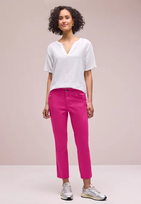Persoon met wit shirt en roze broek voor lichte achtergrond.