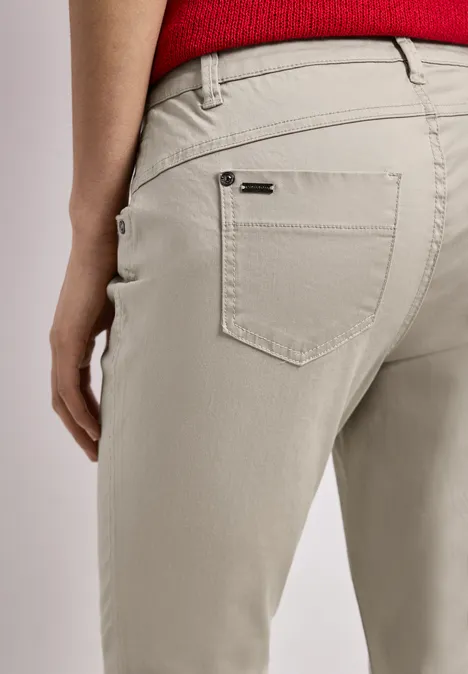 Close-up van persoon in beige broek en rood shirt, nadruk op achterzak.