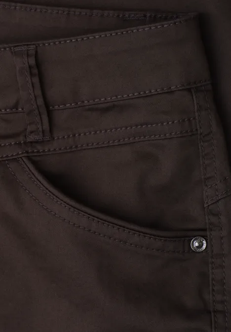 Close-up van een bruine spijkerbroek met zak, riemlussen en klinknagel.