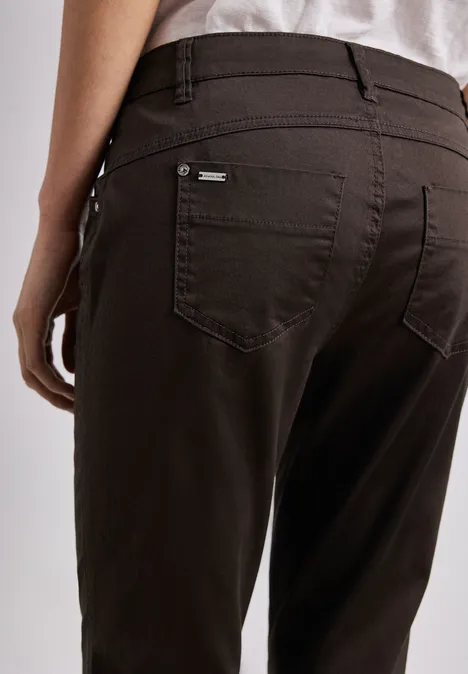 Achteraanzicht van een persoon in donkerbruine broek met achterzakken en deels zichtbaar wit shirt.