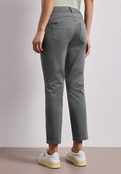 Achteraanzicht van een persoon in grijze broek en witte sneakers.