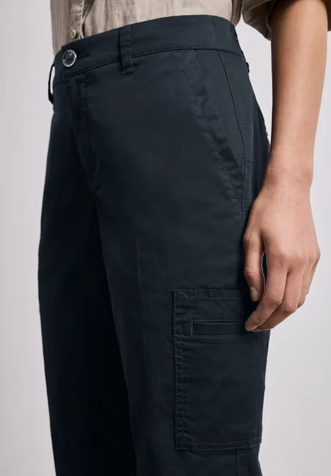 Model draagt donkerblau cargo-broek met zijzak en knoopsluiting.