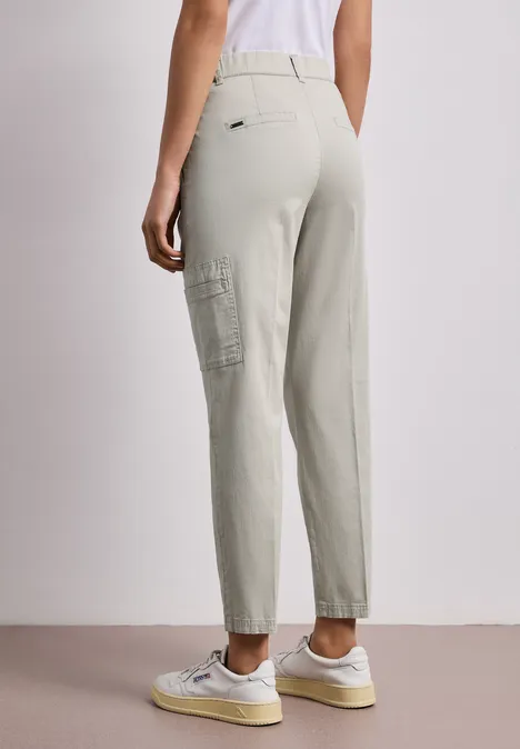 Achteraanzicht van iemand in lichtgrijze cargobroek en witte sneakers.