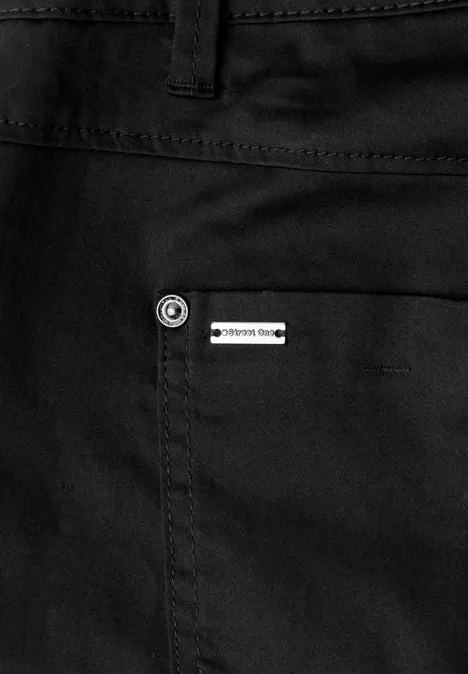 Close-up van een zwarte broekzak met een klein zilverkleurig logo-label.