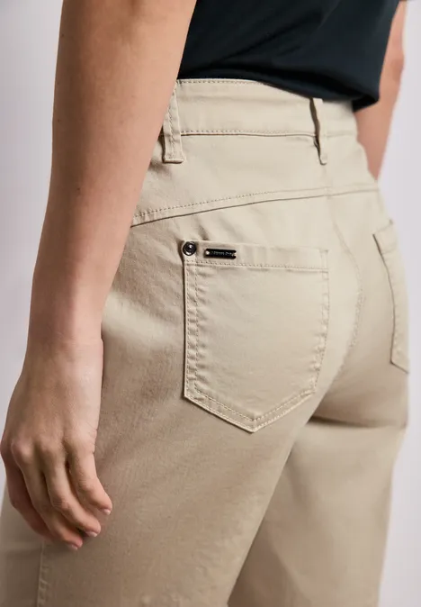 Achteraanzicht van een persoon in beige broek met achterzakken en riemlussen.