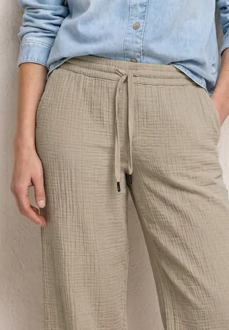 Beige, locker sitzende Hose mit Tunnelzug und Textur, dazu hellblaues Hemd.