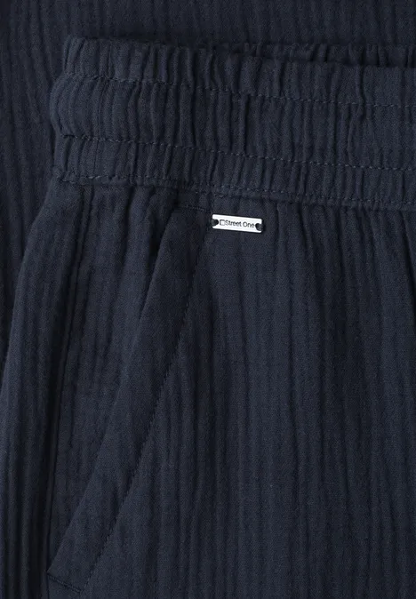 Tissu bleu foncé texturé avec taille élastique, poche latérale et petite plaque métallique