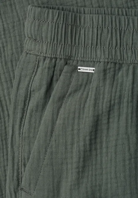 Dunkelgrüne Hose aus leichter gecrinkelter Baumwolle mit elastischem Bund und Seitentasche.