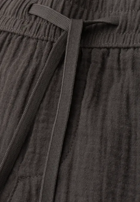 Nahaufnahme einer dunkelgrauen Leinenhose mit Kordelzug und feiner Webstruktur.