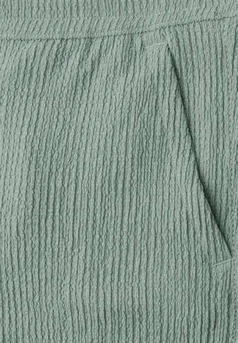 Nahaufnahme einer mintgrünen, texturierten Stoffhose mit Taschennaht