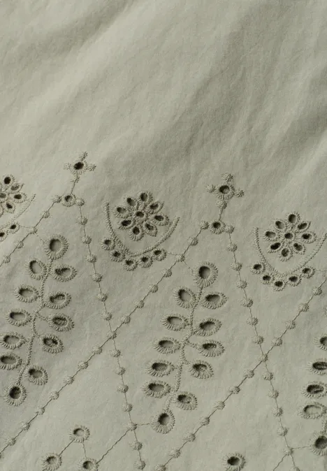 Helles Leinenstoff mit zarten, symmetrischen Blumen- und Blattstickereien.