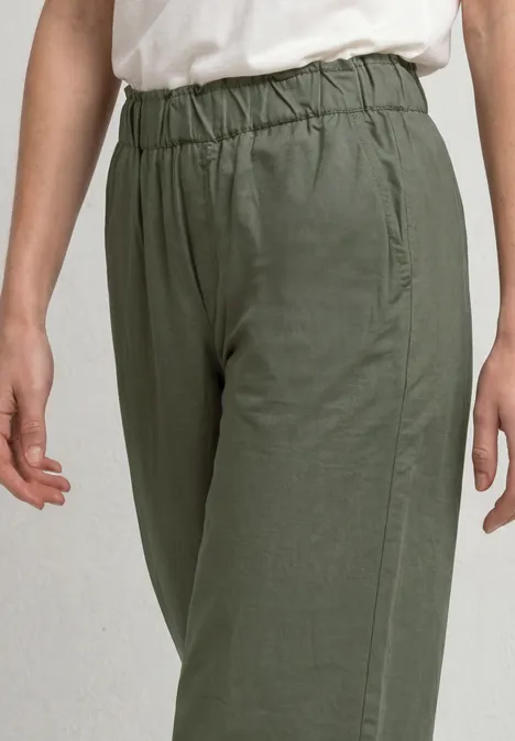 Lässige grüne Hose mit elastischem Bund und Seitentaschen, am Beinanschnitt einer stehenden Person.