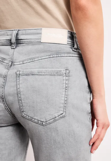 Nahaufnahme einer Person in hellgrauen, eng sitzenden Jeans mit Gesäßtasche.