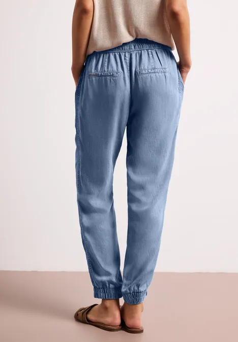 Rückenansicht einer Person in hellblauen Joggpants mit Gummizug und Sandalen.