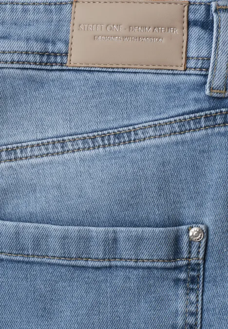 Nahaufnahme einer blauen Jeans mit Fronttasche, Metallniete und Lederetikett am Bund