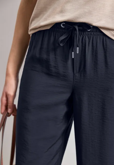 Personne porte un pantalon noir ample à cordon et tient un sac