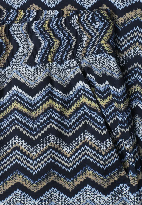 Close-up van een stof met zigzagmotief in blauw, wit, geel en zwart.