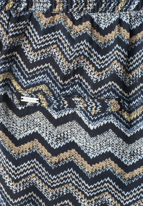 Strickstoff mit blau-weiß-beige Zickzack-Muster und aufgesetzter Reißverschlusstasche.