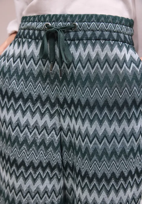 Elastische Hose mit grün-grauem Zickzackmuster und Kordelzug.