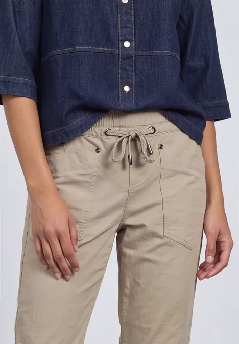 Person trägt beige Leinenhose mit Tunnelzug und dunkles Jeanshemd