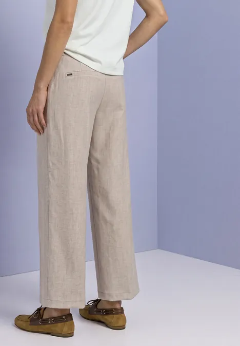 Pantalon Straight Leg, effet chiné fading sand Seitliche Ansicht einer Person mit beigen weiten Leinenhosen, weißem Top und braunen Loafers.