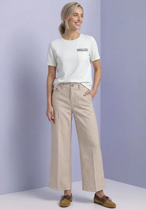 Pantalon Straight Leg, effet chiné fading sand Eine lächelnde Frau in weißem T-Shirt und weiten, beige Leinenhosen mit Taschen und Loafers vor lila Hintergrund.