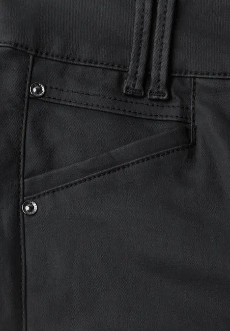 Gros plan sur un pantalon noir, poche en biais ornée de rivets