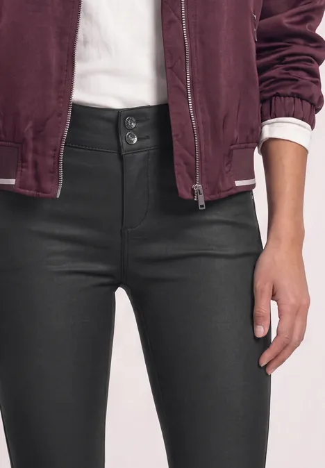 Femme en jeans taille haute noir à double bouton, t-shirt blanc et veste bordeaux, main posée sur la cuisse.
