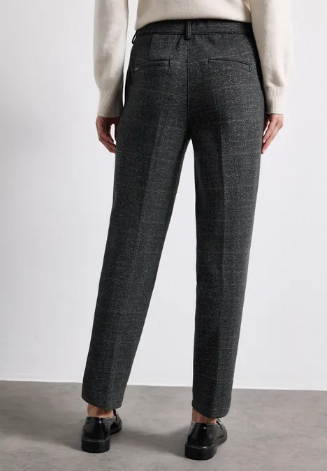Eine Person trägt dunkelgraue, karierte Stoffhose im geraden Schnitt und schwarze Loafer.