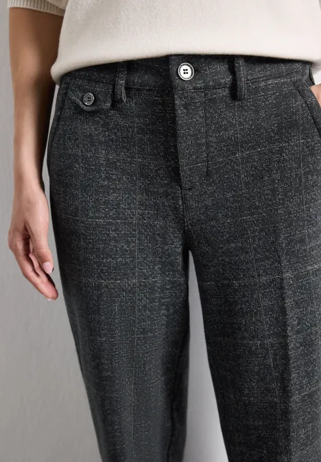 Seitlicher Blick auf eine dunkelgraue, karierte Hose mit Knöpfen, kombiniert mit einem hellen Oberteil.