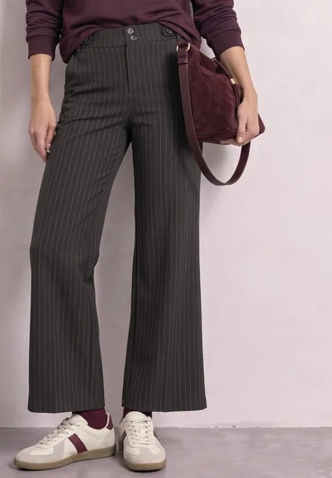 Pantalon large noir à fines rayures, baskets blanches avec détail bordeaux et sac assorti.