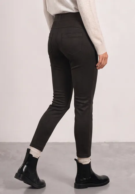 Vue arrière d’une personne portant un pantalon noir moulant et des bottines noires avec doublure blanche.