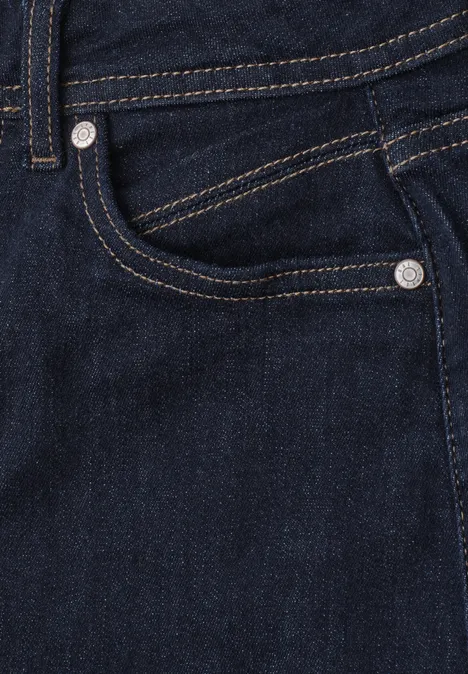 Nahaufnahme einer dunklen Jeanshose mit sichtbarer Tasche und Ziernähten.