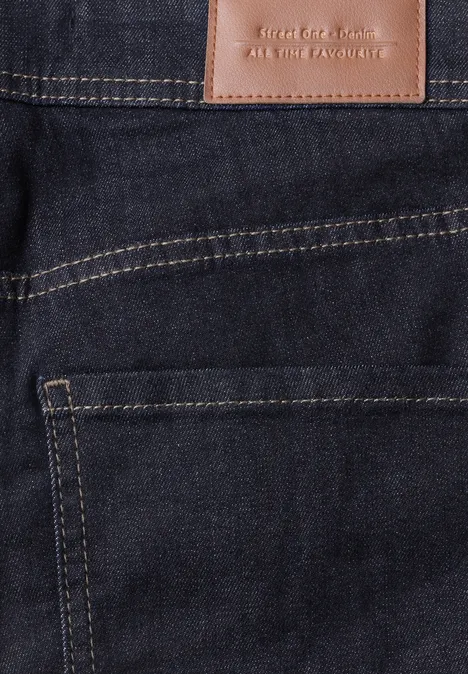 Nahaufnahme einer dunkelblauen Jeans mit braunem Lederpatch und gelben Nähten an der Gesäßtasche.