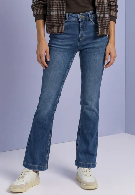 Personne porte un jean évasé bleu foncé, des baskets blanches, un top noir et une veste à carreaux.